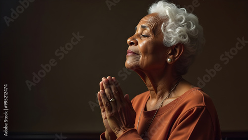 An elderly African American woman prays. photo