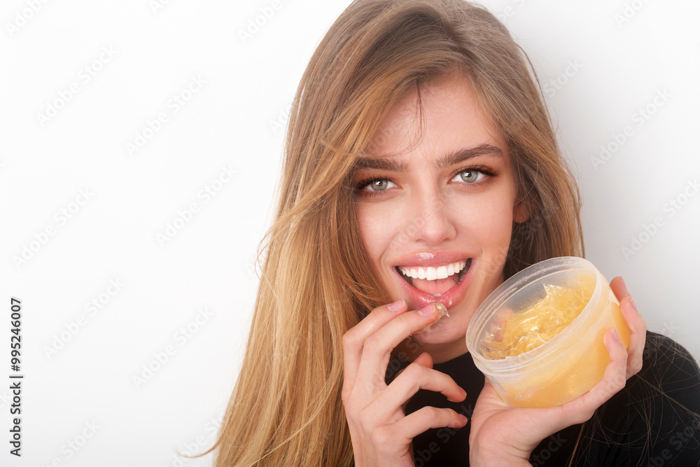 Facial treatment. Woman lips balm. Girl enjoying a facial treatment with a lips cream. Lips skin care. Young woman hold cream jar. Portrait of beauty woman with cream for healthy lips. Gold cosmetics. Facial treatment. Woman lips balm. Girl enjoying a facial treatment with a lips cream. Lips skin care. Young woman hold cream jar. Portrait of beauty woman with cream for healthy lips. Gold cosmetics.