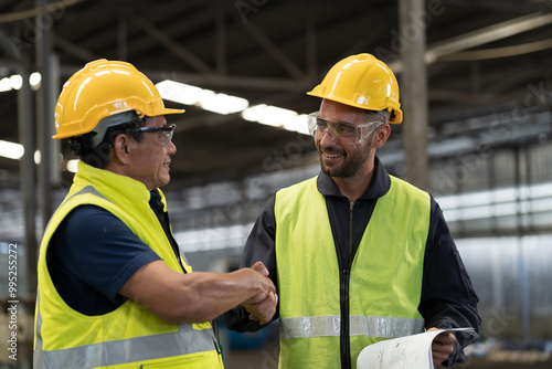 Two male engineer join hands together in industry factory. Finished, completed work concept