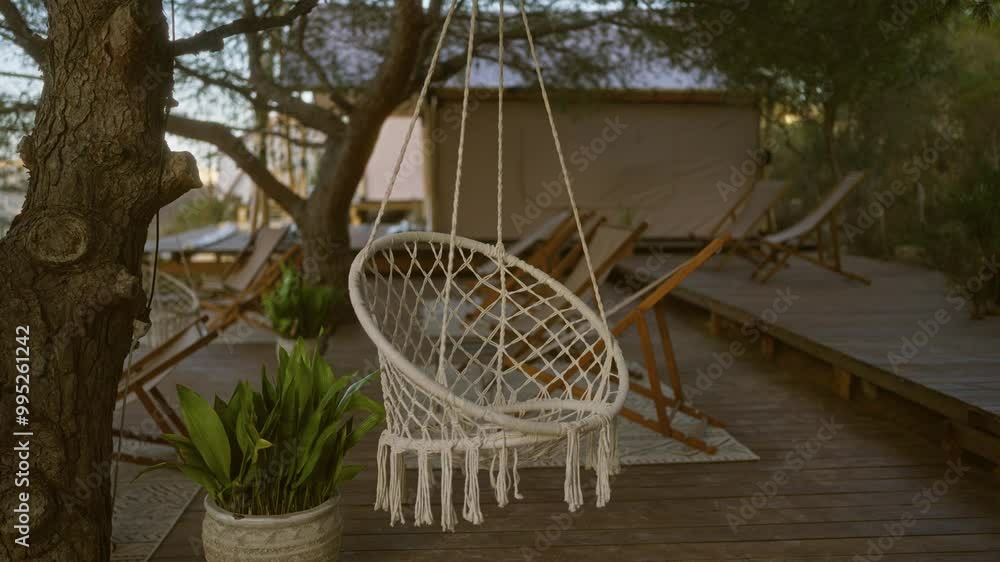 A serene outdoor setting featuring a hammock chair, deck, potted plant, and lounge chairs surrounded by trees, creating a relaxing and peaceful environment. A serene outdoor setting featuring a hammock chair, deck, potted plant, and lounge chairs surrounded by trees, creating a relaxing and peaceful environment.