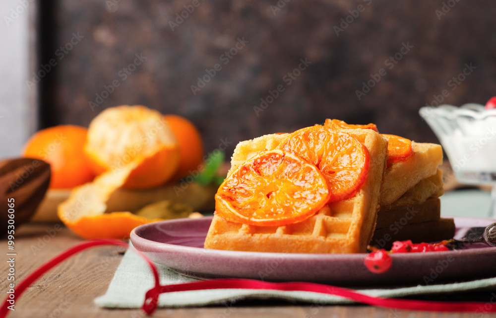 Sweet Belgian waffles with caramelized orange on a pink purple plate. Christmas breakfast. Xmas theme. Sweet Belgian waffles with caramelized orange on a pink purple plate. Christmas breakfast. Xmas theme.