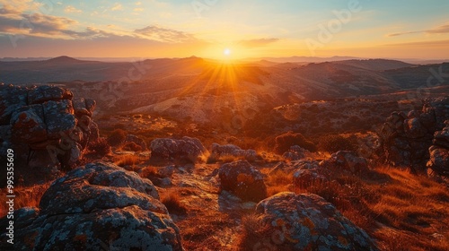 A dramatic sunrise over a rugged, rocky terrain, with the sun rising over the horizon, casting a long shadow across the rugged landscape photo