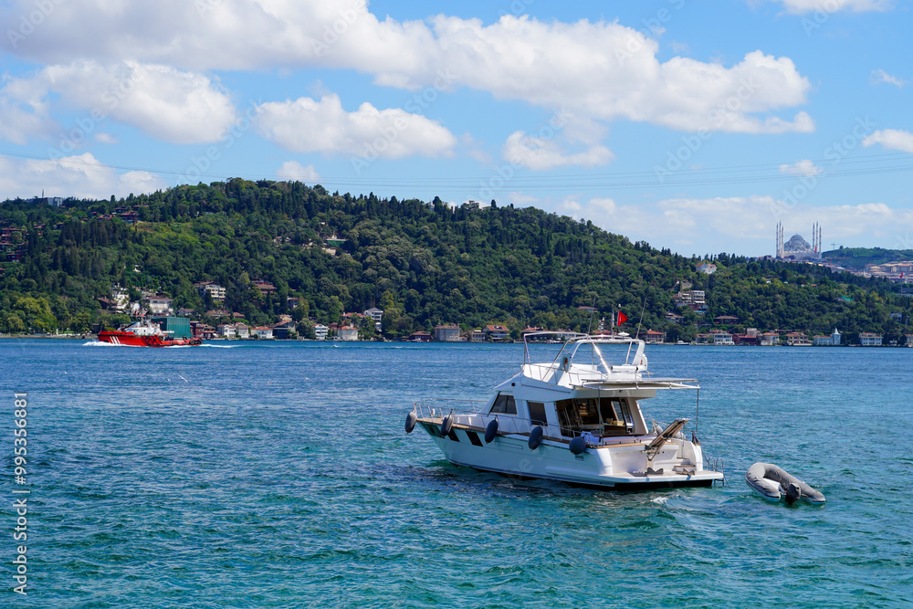 Luxury yacht sailing on the serene Bosphorus with lush green hills and an Istanbul mosque in the backdrop Luxury yacht sailing on the serene Bosphorus with lush green hills and an Istanbul mosque in the backdrop