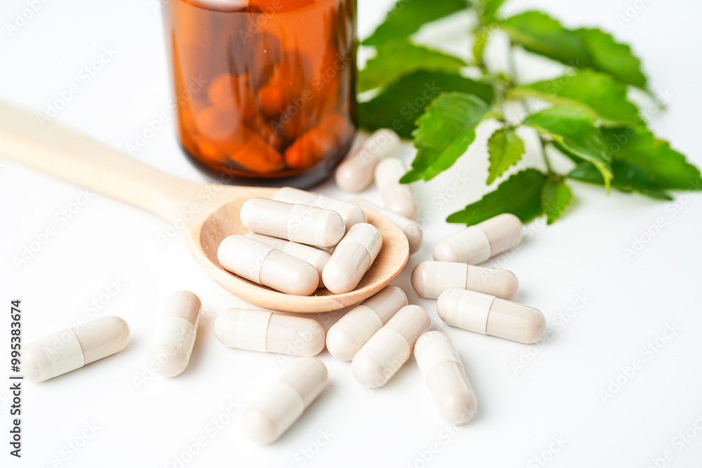 Vitamin herbal capsules in a wooden spoon and bottles on with background Vitamin herbal capsules in a wooden spoon and bottles on with background
