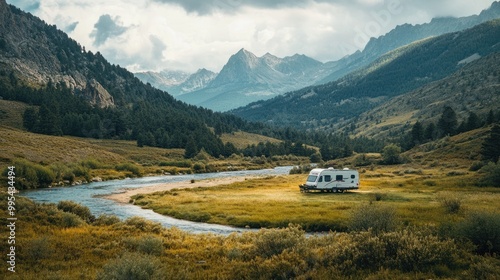 A travel trailer in a scenic valley, with mountains and a river nearby