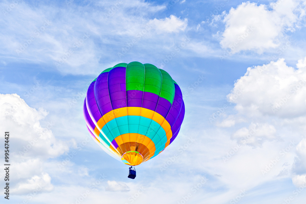 Naklejka premium Colorful hot air balloon flying over blue sky with white clouds