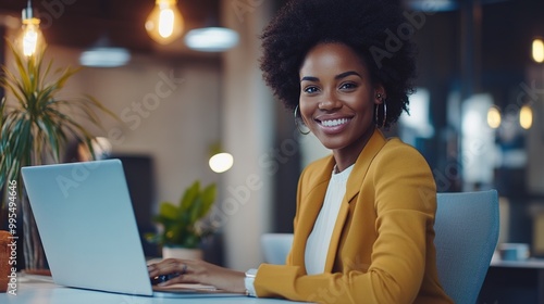 Professional Woman Smiling at Laptop in Modern Office