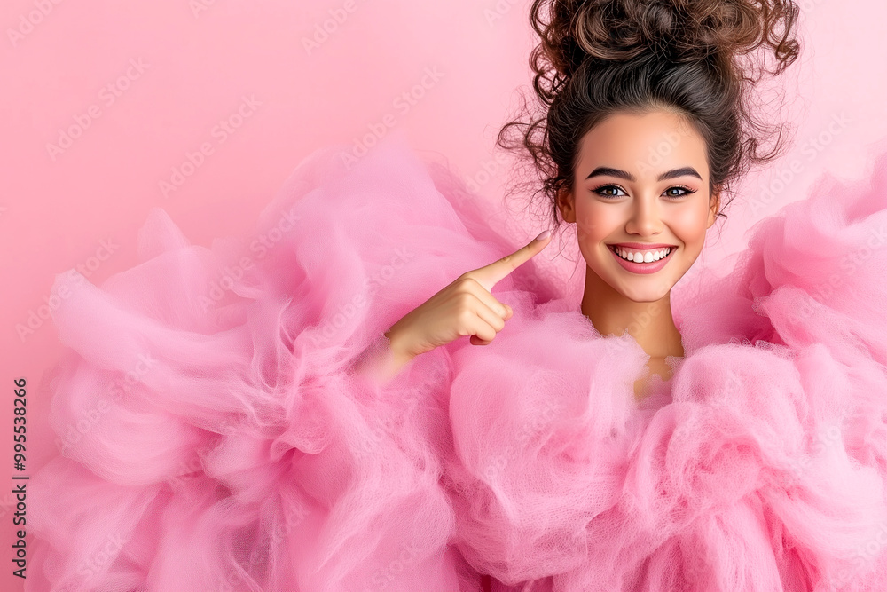 A woman in a pink dress is smiling and pointing to her mouth. The pink dress is made of a fluffy material, giving it a soft and comfortable appearance A woman in a pink dress is smiling and pointing to her mouth. The pink dress is made of a fluffy material, giving it a soft and comfortable appearance
