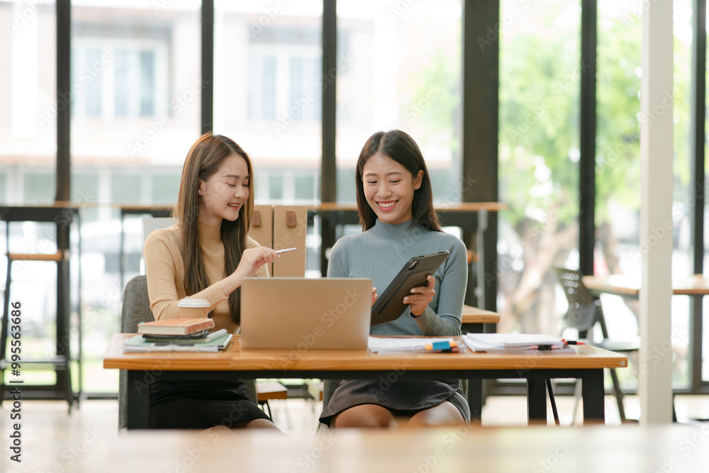 Asian businesswoman using a tapered laptop, sitting and talking in the office Asian businesswoman using a tapered laptop, sitting and talking in the office
