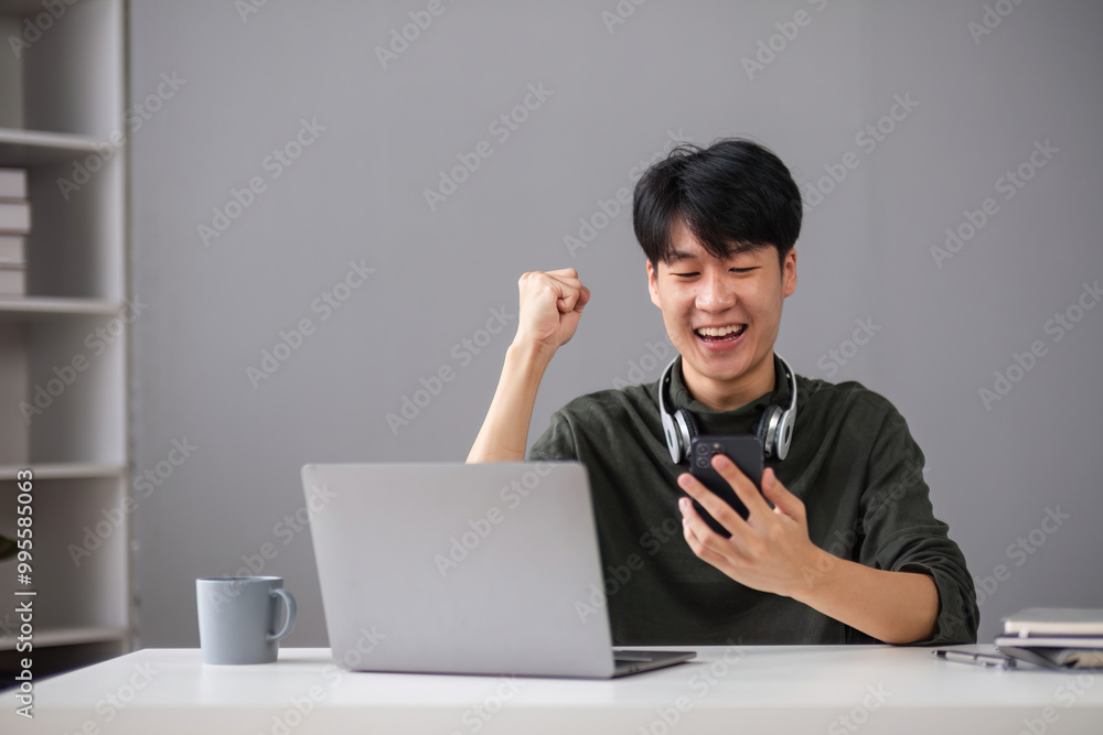 Young Boy Studying Online with Laptop and Smartphone, Celebrating Success in Modern Home Environment Young Boy Studying Online with Laptop and Smartphone, Celebrating Success in Modern Home Environment