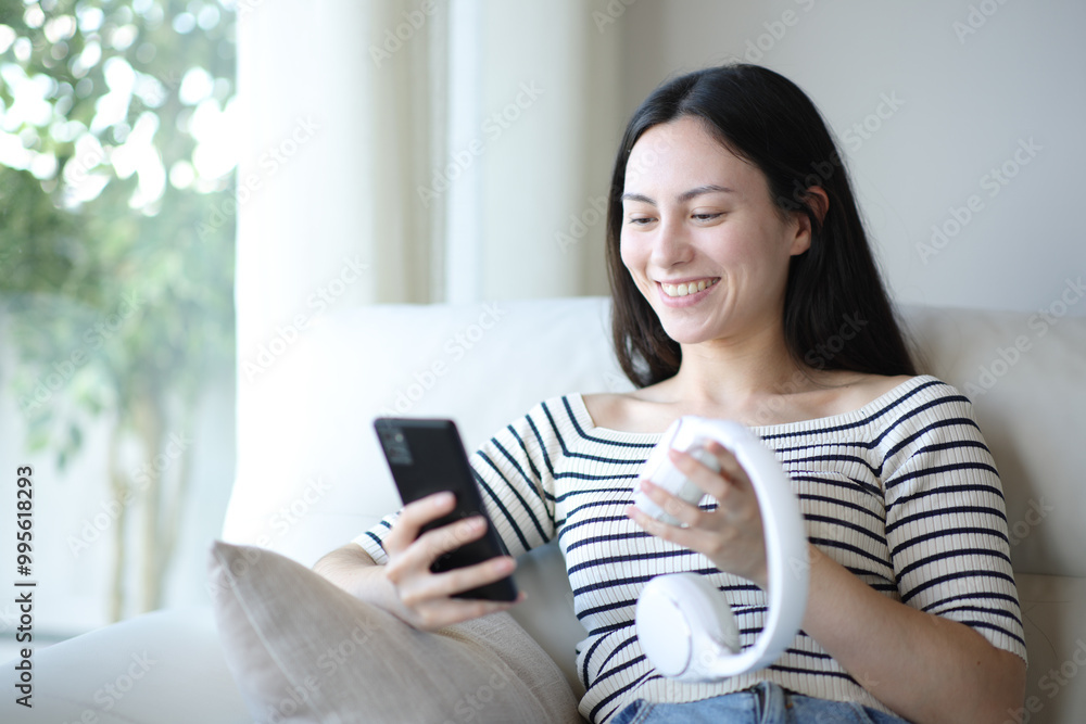 Happy asian woman pairing headphone and phone at home Happy asian woman pairing headphone and phone at home