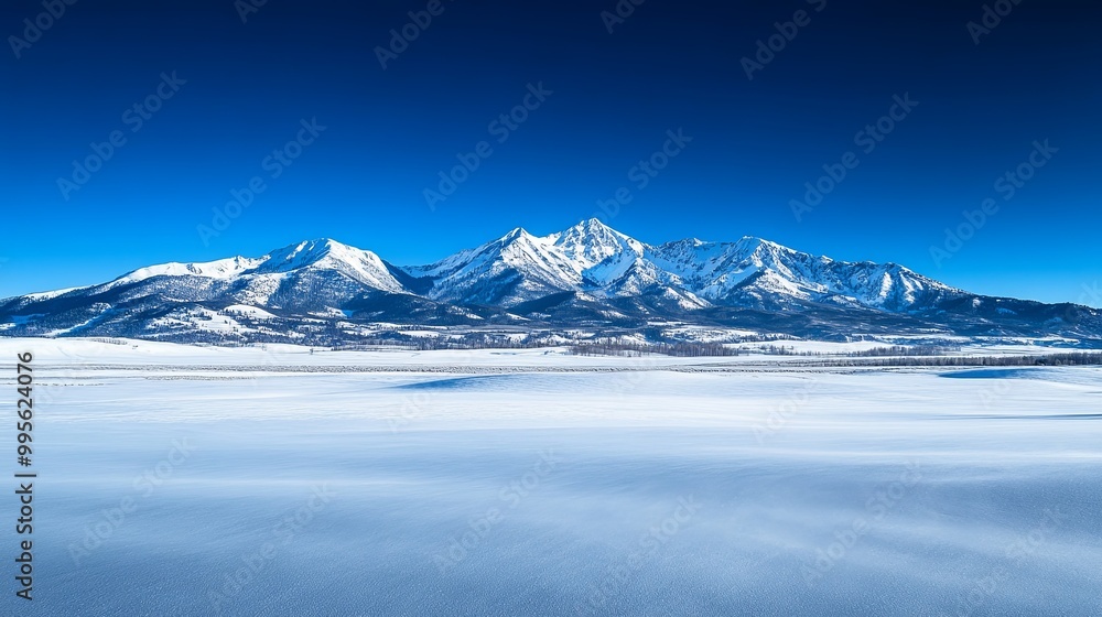 Obraz premium A serene winter landscape featuring snow-covered mountains under a clear blue sky.
