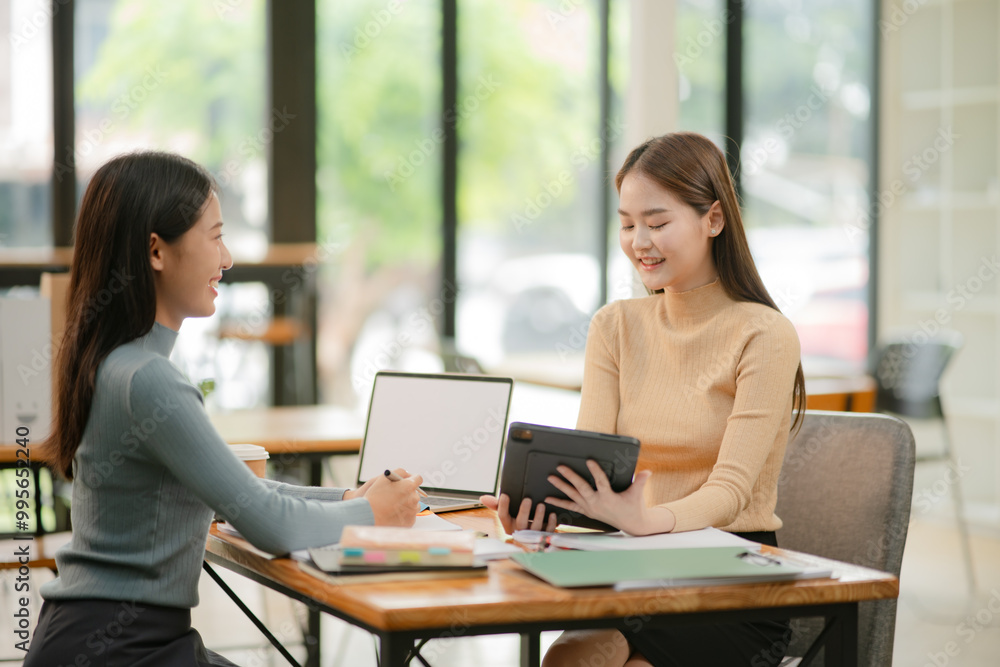 Asian businesswoman using a tapered laptop, sitting and talking in the office Asian businesswoman using a tapered laptop, sitting and talking in the office