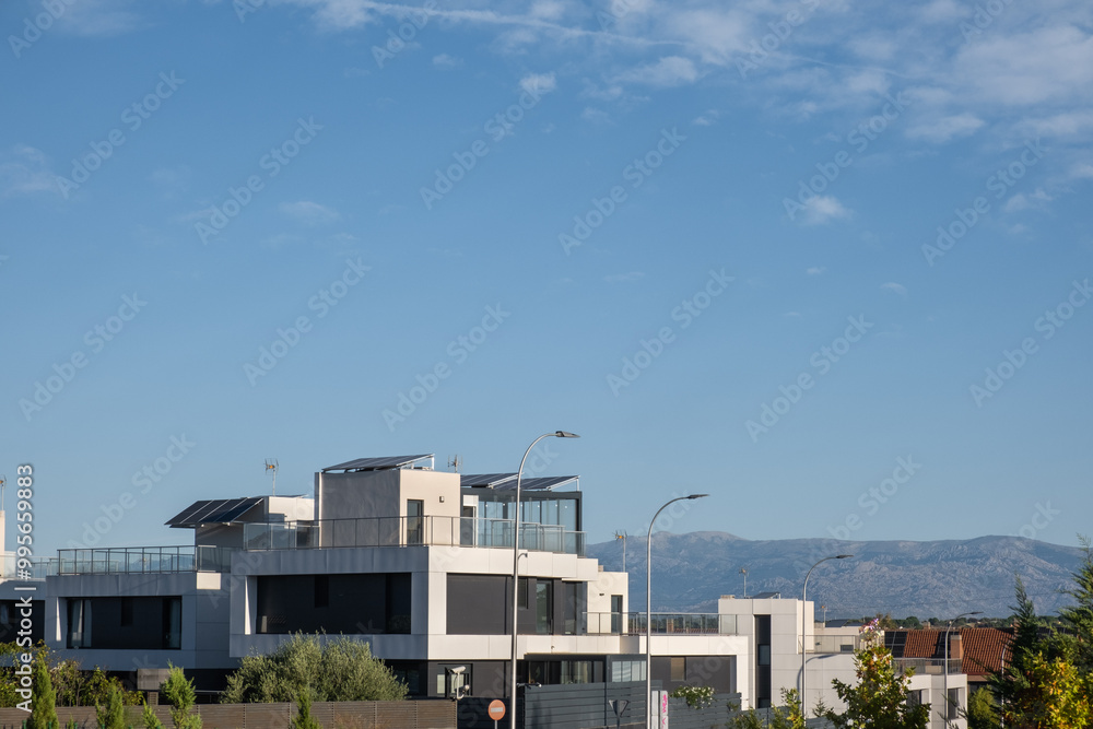 It dawns in an urbanization of individual chalets with modern architecture. They have photovoltaic solar panels on the roofs, the sky is clear and blue. Sustainability and sustainable urbanism It dawns in an urbanization of individual chalets with modern architecture. They have photovoltaic solar panels on the roofs, the sky is clear and blue. Sustainability and sustainable urbanism