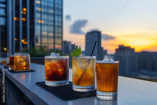 Classic cocktails served on a rooftop bar with a city view..Drinks lined up on a table with a cityscape view behind