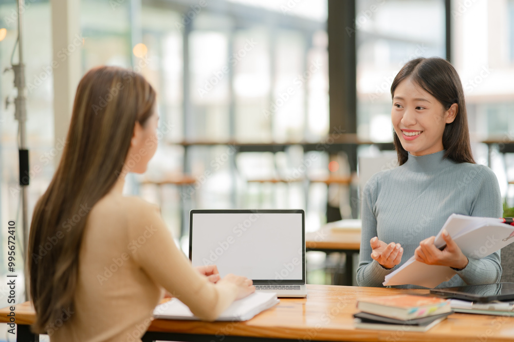 Asian businesswoman using a tapered laptop, sitting and talking in the office Asian businesswoman using a tapered laptop, sitting and talking in the office