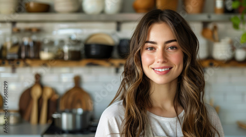 smiling blonde female cooking blogger with long brown hair against a modern minimalist kitchen background with cooking utensils