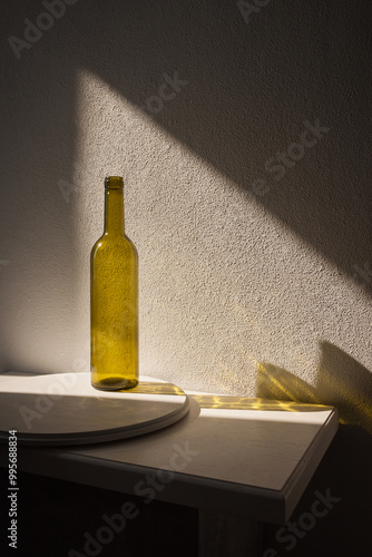 A bottle of wine in sunlight and its colored shadow. long shadow and refraction patterns. White background