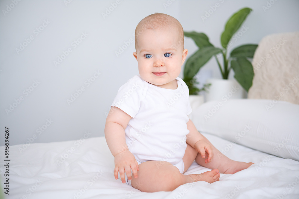 portrait of smiling healthy baby in white bodysuit sitting on bed. copy space portrait of smiling healthy baby in white bodysuit sitting on bed. copy space