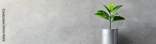 A vibrant green plant growing in a metallic can, symbolizing ecofriendliness and sustainability in a modern setting photo