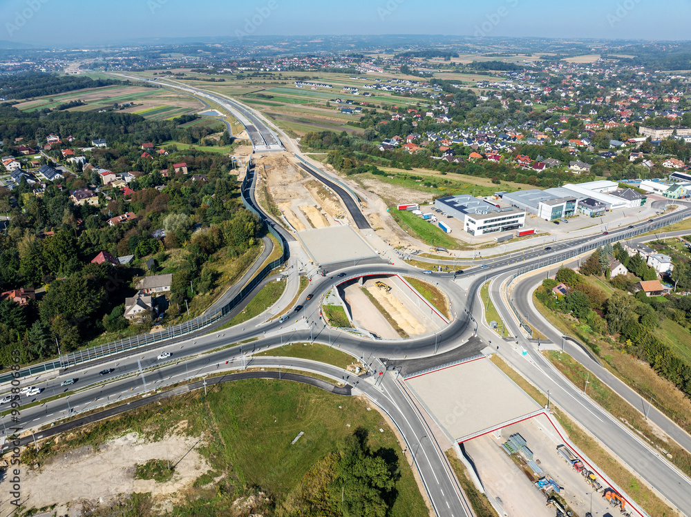 Krakow, Poland. Wegrzce highway interchange in construction on S53, part of motorway ring way around Cracow. Traffic circle with a hole inside, viaducts, tunnels and ramps. September 2024. Aerial view
