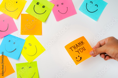 Thank you and smile icon inspirational handwriting on sticky notes on hand held