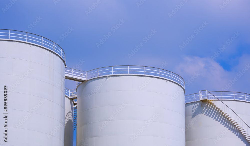 Crude Oil Industrial, Row of White Storage Fuel Tanks Group in Petroleum Refinery area against Cloudy Sky Background Crude Oil Industrial, Row of White Storage Fuel Tanks Group in Petroleum Refinery area against Cloudy Sky Background