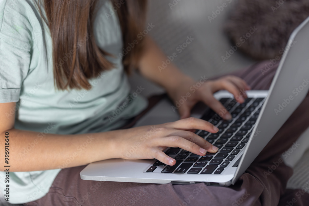 The girl is typing on the laptop keyboard. Girl's hands on the keyboard. The girl is typing on the laptop keyboard. Girl's hands on the keyboard.
