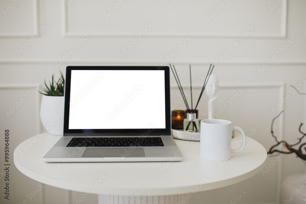 Fototapeta premium Laptop and white mug with tea on a table. Workspace in a modern room.