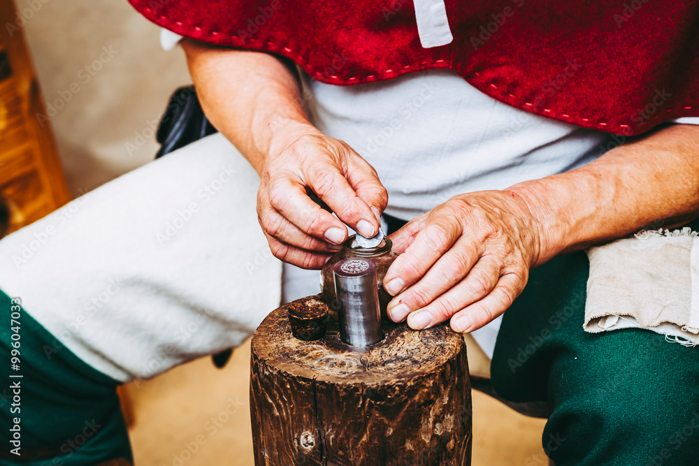 Main d'un artisan en train de fabriquer des pièces de monnaie en métal à l'ancienne