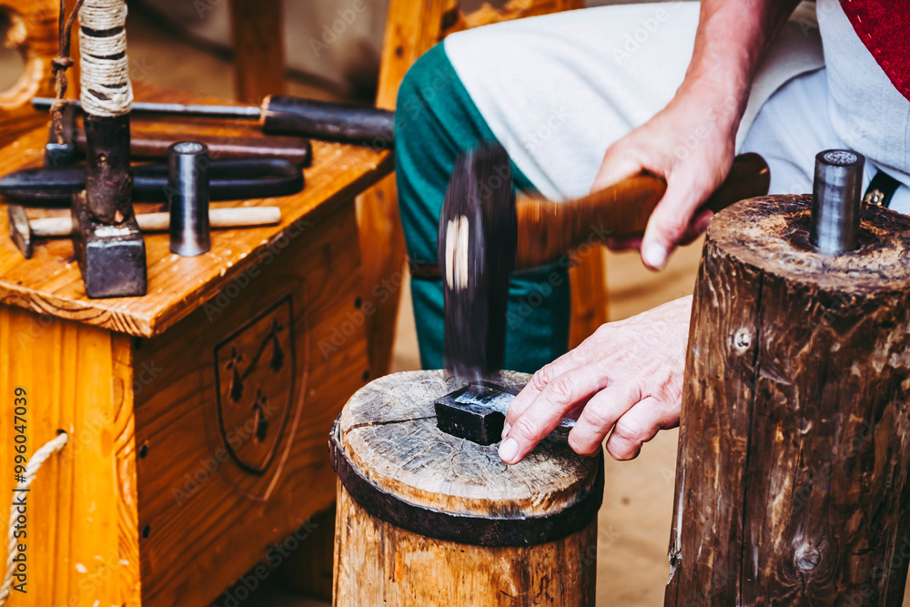 Main d'un artisan en train de fabriquer des pièces de monnaie en métal à l'ancienne