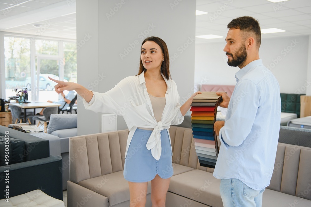 Fototapeta premium Focus on samples of colored fabrics for upholstered furniture. Overhead view of couple choosing color and fabric texture for upholstery sofa in the home. Interior design concept.