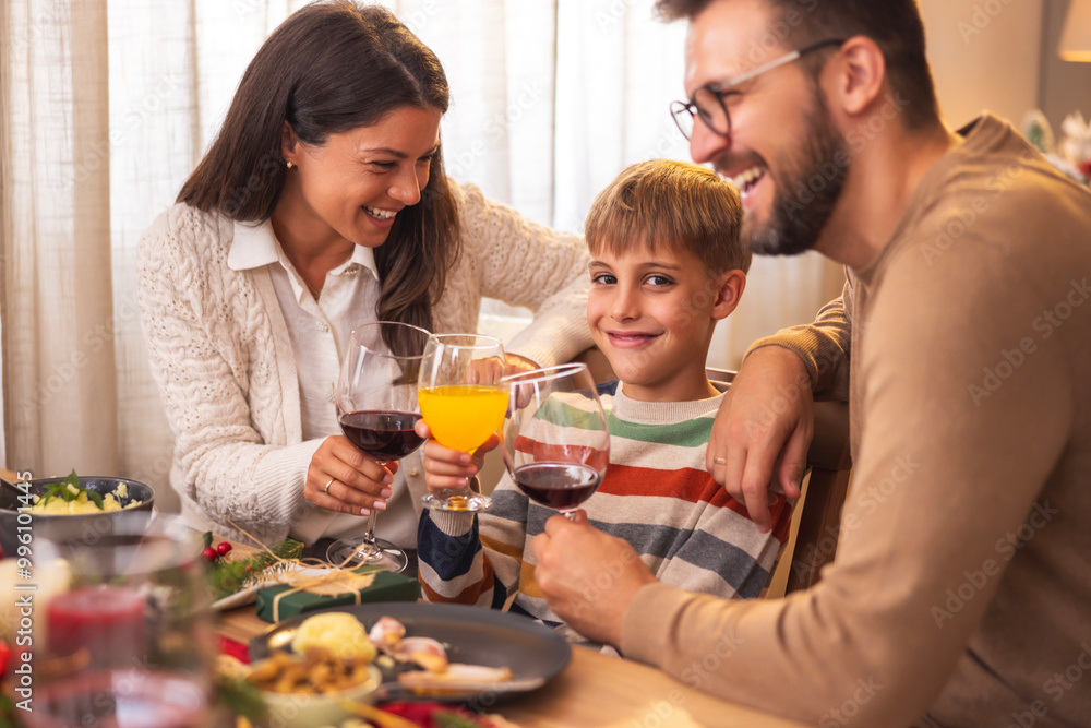 Parents making a toast with son while having Christmas dinner Parents making a toast with son while having Christmas dinner