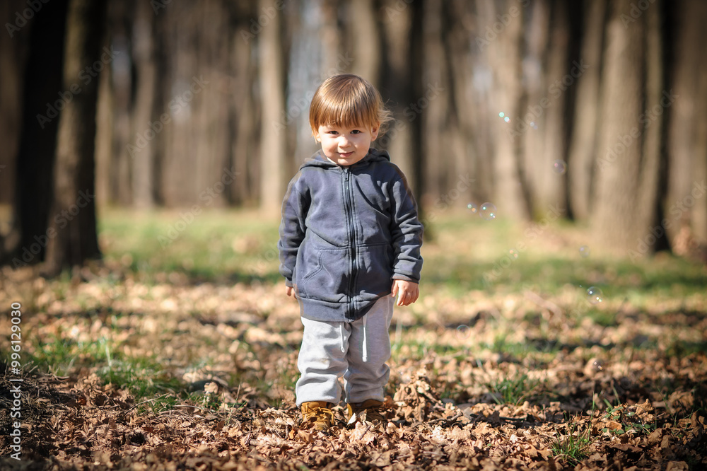 A curious child exploring autumn leaves in a sunlit forest during a joyful day of play and discovery A curious child exploring autumn leaves in a sunlit forest during a joyful day of play and discovery