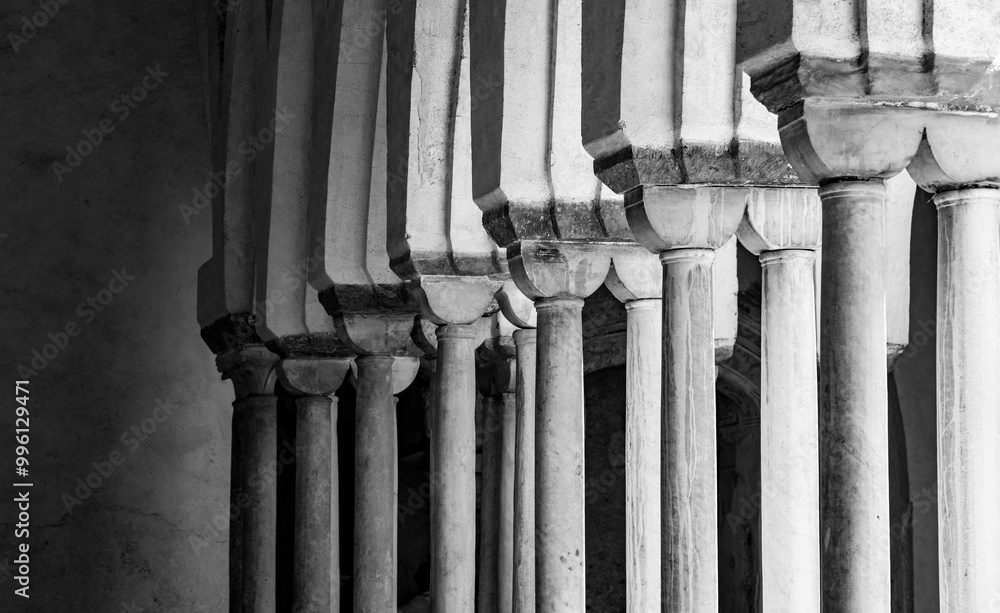 Columns and arches in the cloister of the “Cattedrale di Sant'Andrea“, the cathedral of Amalfi (Italy) and famous monument and tourist attraction. Light flashing in through the old historic arcades. Columns and arches in the cloister of the “Cattedrale di Sant'Andrea“, the cathedral of Amalfi (Italy) and famous monument and tourist attraction. Light flashing in through the old historic arcades.