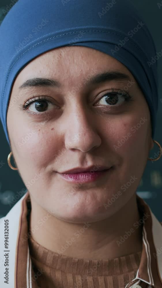 Vertical medium closeup portrait of young adult Muslim female student posing for camera in front of blackboard Vertical medium closeup portrait of young adult Muslim female student posing for camera in front of blackboard
