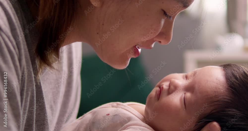 Singing a sweet lullaby to her sleeping newborn child, a mother wakes her baby from its sleep. Singing a sweet lullaby to her sleeping newborn child, a mother wakes her baby from its sleep.