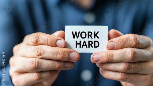 Close-up of hands holding a small card with the motivational message 'Work Hard'. Concept of motivation, dedication, and perseverance. photo