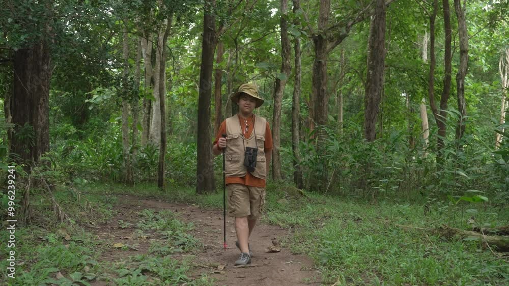 A front view of a teenage Asian boy walking on a nature trail in the forest, exploring nature and seeking adventure A front view of a teenage Asian boy walking on a nature trail in the forest, exploring nature and seeking adventure