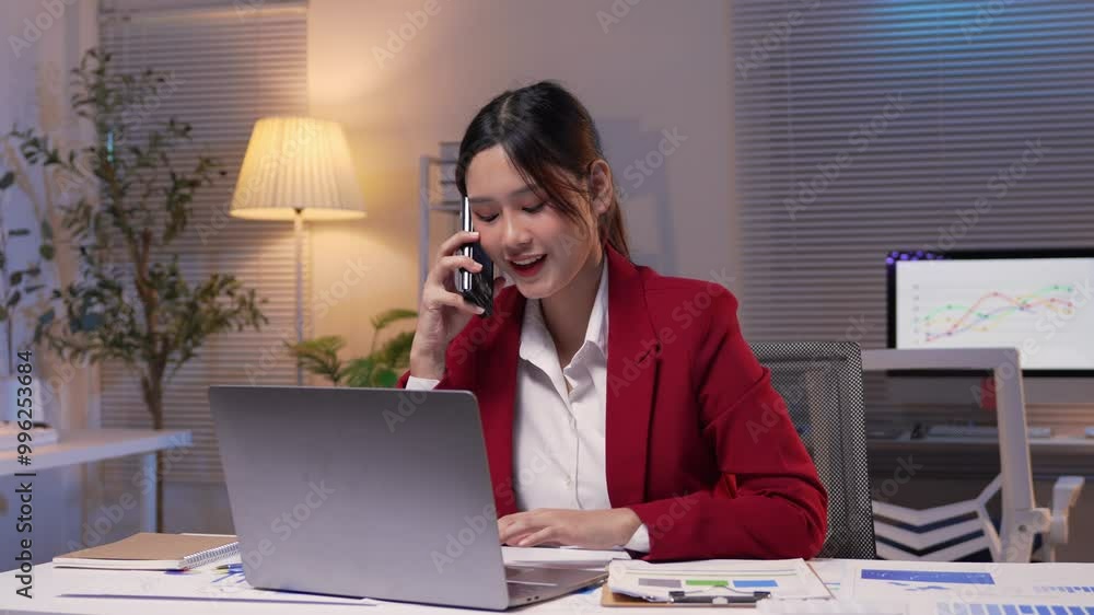 Businesswoman is working late in her office when she receives a phone call that makes her very happy Businesswoman is working late in her office when she receives a phone call that makes her very happy