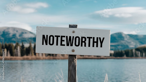 White sign with black text Noteworthy against a blue lake and mountain backdrop. Motivational and inspirational concept. 
