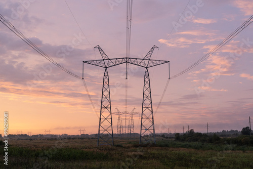 High voltage pylons against the dramatic cloudy sky. Power lines stretching into the distance. Perspective. Electricity