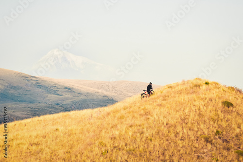 Fit young caucasian male person push bicycle uphill with mountains background outdoors in caucasus mountains. Achievement , inspiration, challenge and determination concept