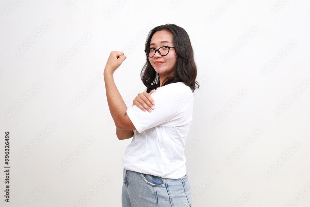 Side view young strong woman in casual showing biceps muscles on hand isolated on white background Side view young strong woman in casual showing biceps muscles on hand isolated on white background