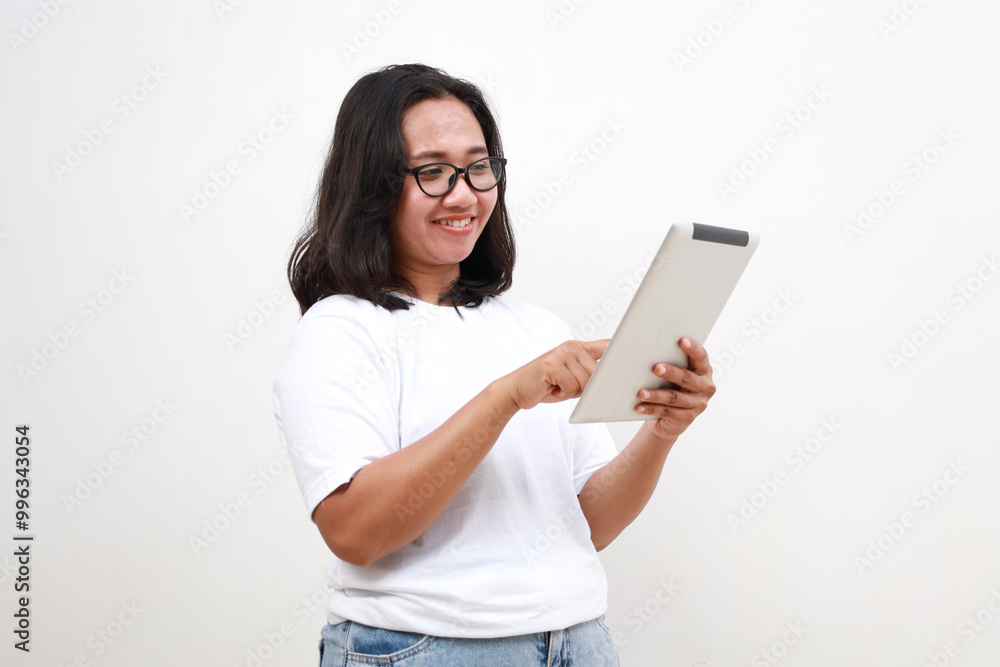 Smiling busy young asian business woman manager using tablet computer, happy business woman executive looking at tab device analyzing finance trading market data working standing over white background Smiling busy young asian business woman manager using tablet computer, happy business woman executive looking at tab device analyzing finance trading market data working standing over white background