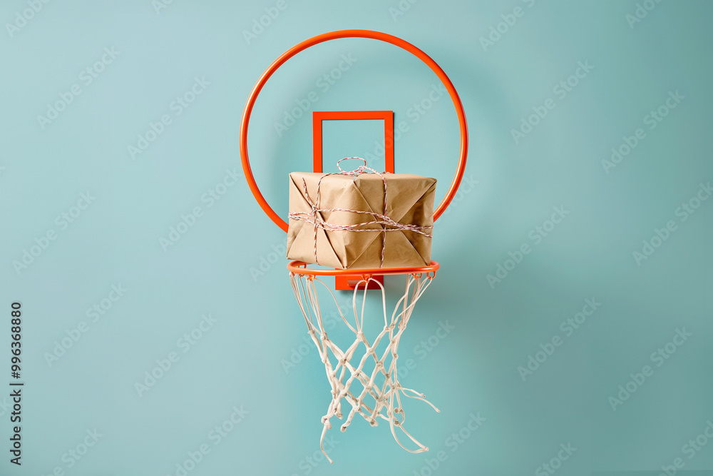Giftbox is falling in basketball hitting net. A parcel wrapped in craft paper is falling inside the basketball hoop. Success in action, right choice, good work concept. High quality delivery service Giftbox is falling in basketball hitting net. A parcel wrapped in craft paper is falling inside the basketball hoop. Success in action, right choice, good work concept. High quality delivery service