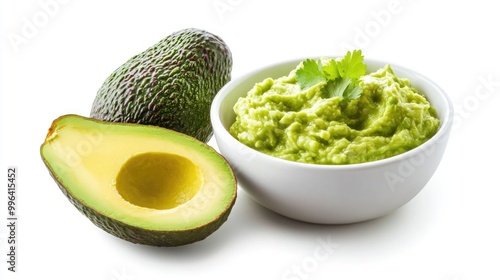 Half avocados alongside a bowl of guacamole sauce set against a white backdrop