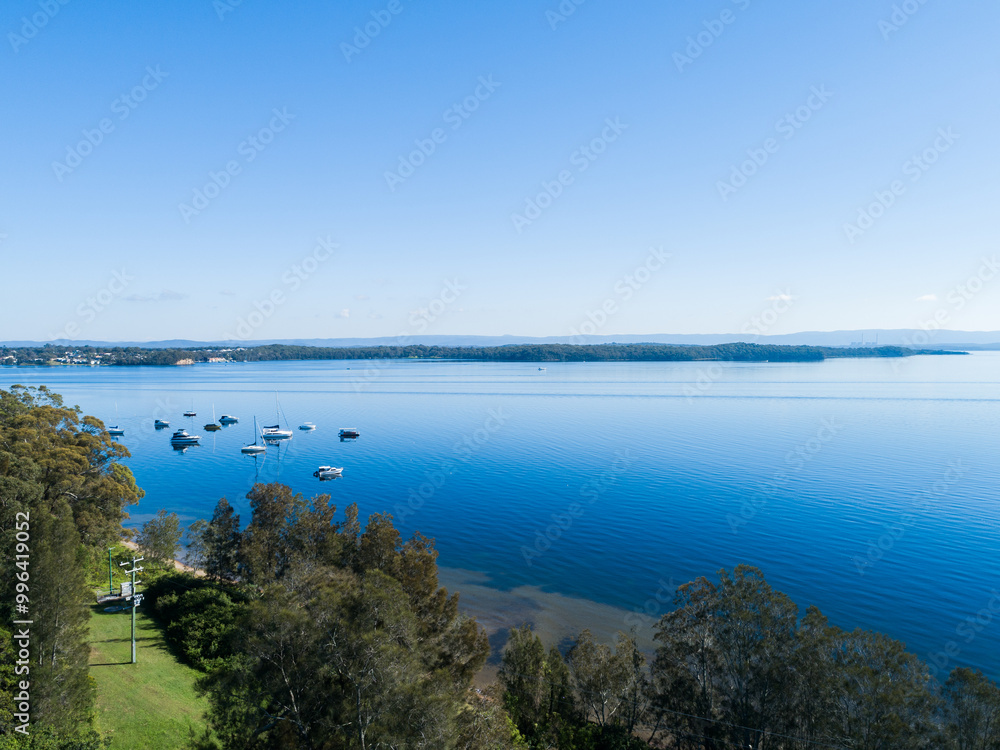 Recreational boats moored in water of Lake Macquarie in bright sunlight seen from aerial view Recreational boats moored in water of Lake Macquarie in bright sunlight seen from aerial view