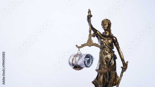 Themis statue, the Greek goddess of justice and a US dollar bill hanging on the scales of justice on a white background. the concept of bribery, the decision of justice photo