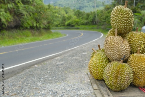 Durians for sale on wooden table. Street as background. Harvest from durians garden near it. Durian photo